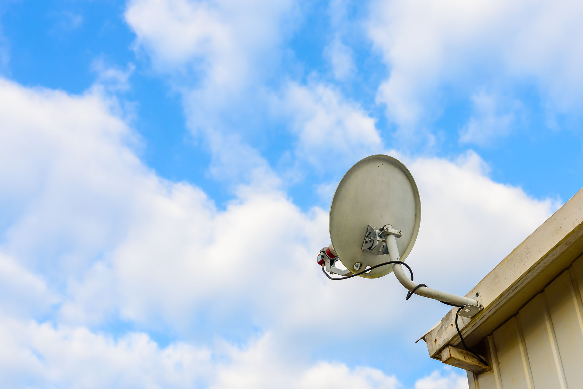 Viasat dish mounted at the roof line of a home.